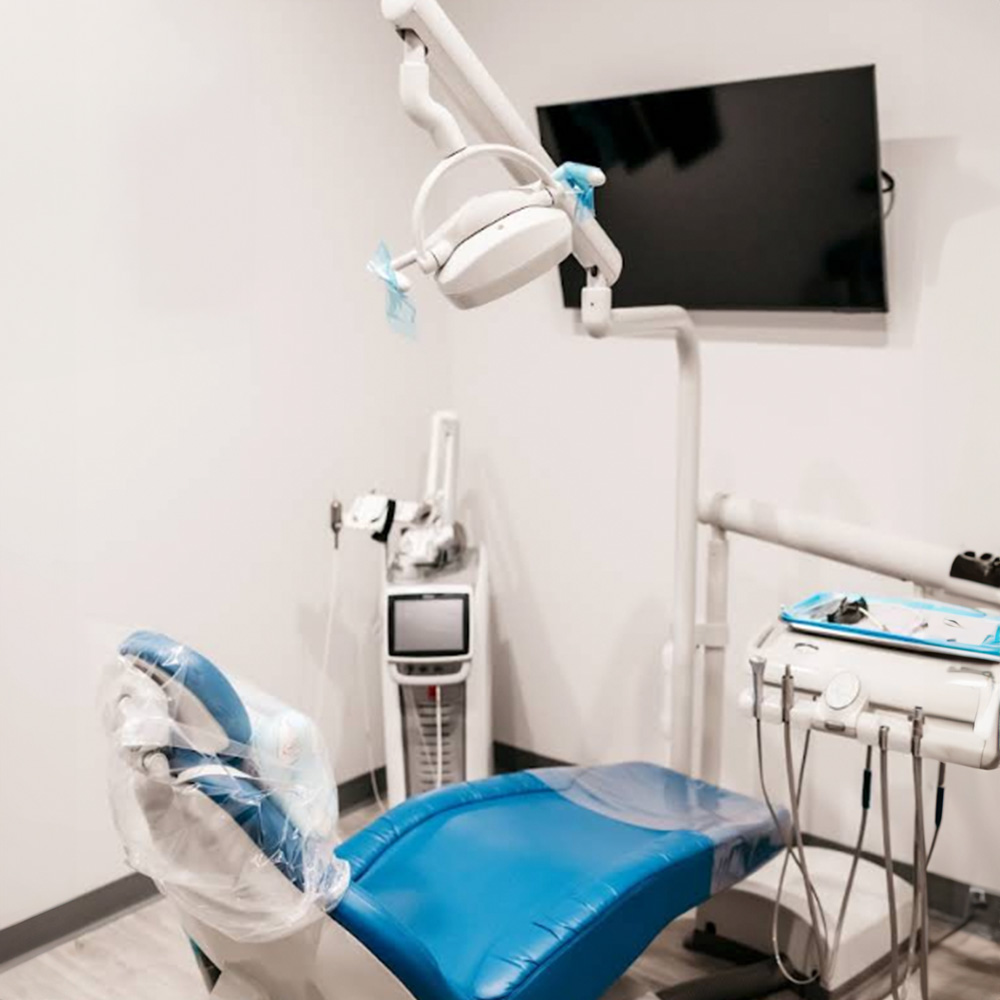 The image shows a dental office interior with a dental chair, a dental light, and various dental equipment.